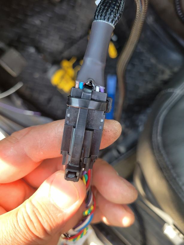 Close-up of a vehicle wiring harness connector held in a technician's hand