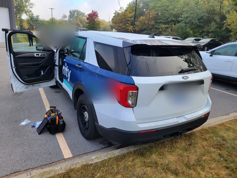 Security patrol SUV with door open and tool bag staged for a camera install
