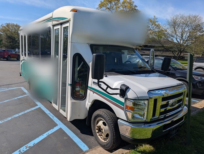 Cutaway shuttle bus staged in a parking lot for a camera and telematics install